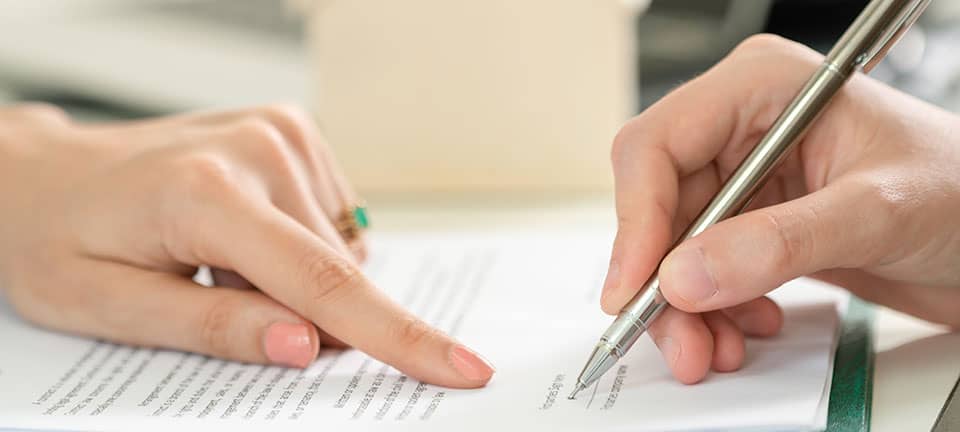 Änderungen in 2022 - Vertragsrecht: Zeigefinger einer Frauenhand zeigt an, wo auf dem Vertrag unterschrieben werden soll, Männerhand mit Stift setzt zum Unterschreiben an.