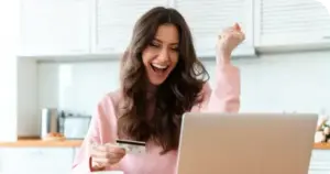 Frau sitzt vor Laptop und freut sich