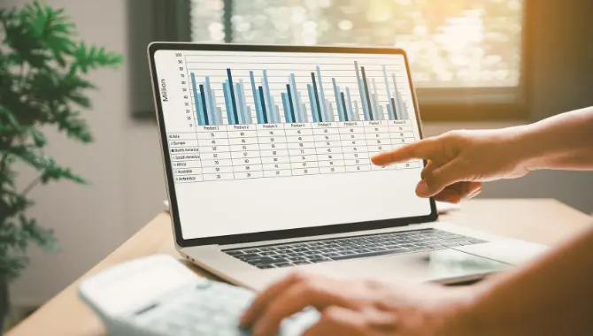 Person zeigt auf Laptop mit Zahlen und Grafiken
