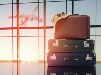 aufgestapelte Koffer, im Hintergrund ein Flugzeug