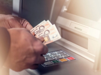 Hände nehmen Geld aus einem Geldautomaten